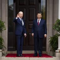 Biden stands on the left waving , Jinping stands to the right with his arms at his sides