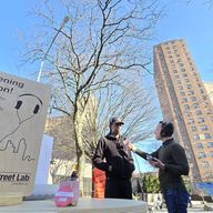 A reporter interviewing a man on Thatford Avenue in Brooklyn. A public housing complex is in the background.