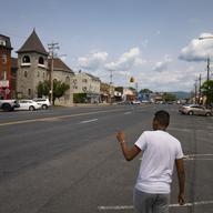 Mohamed, a 19-year-old fleeing political persecution in the northwest African country of Mauritania, points in the direction of his prospective work opportunity, Monday, May 22, 2023, in Newburgh, N.Y