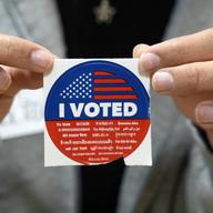 A election volunteer offers voters an 'I Voted' sticker after casting their ballot on Super Tuesday, at the Ranchito Elementary School polling station in the Panorama City section of Los Angeles, Tues