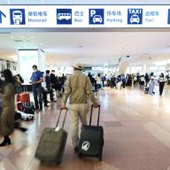 Flight passengers walk through an arrival floor past Chinese and English signs indicating transportations to leave the Haneda International Airport in Tokyo on Jan. 14, 2023. 