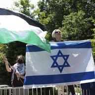 Counter protester Caren Ayden, of Pikesville, Md., carries an Israeli flag as students wave Palestinian flags during a demonstration against the Israel-Hamas war at George Washington University in Was