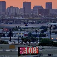 A sign displays an unofficial temperature as jets taxi at Sky Harbor International Airport at dusk, July 12, 2023, in Phoenix.