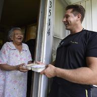 Special Operator 1st Class Brandon Peterson, a member of the U.S. Navy parachute demonstration team, the Leap Frogs, delivers Meals-on-Wheels to elderly and homebound residents as part of Minneapolis/