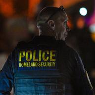A Department of Homeland Security agent stands guard as protesters demonstrate against recent raids conducted by the US Immigration and Customs Enforcement (ICE) outside the DHS office in Charlotte, N