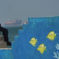 A Cargo boat navigates the sea behind a mural depicting fishes at the shoreline on April 28, 2026 on Qeshm Island, Iran in the Strait of Hormuz.