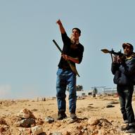 Libyan rebel fighters hold a rocket propelled grenade launcher (RPG) as a pro Kadhafi fighter jet fly over the eastern oil port city of Ras Lanuf on March 11, 2011.