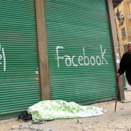 An Egyptian anti-government demonstrator sleeps on the pavement under spray paint that reads 'Al-Jazeera' and 'Facebook' at Cairo's Tahrir square on February 7, 2011 