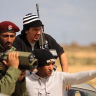Libyan rebels look at government troops position as they massed for a second day on several kilometres from the key city of Ajdabiya on March 22, 201