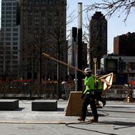 Workers are planting trees and putting in benches at the 9/11 Memorial, World Trade Center,