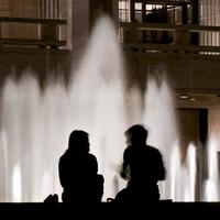 silhouettes of a couple of people in front of the Lincoln Center fountain