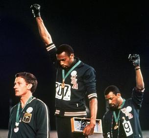 In this Oct. 16 1968, file photo, Australian silver medalist Peter Norman, left, stands on the podium as Americans Tommie Smith, center, and John Carlos raise their gloved fists in protest.