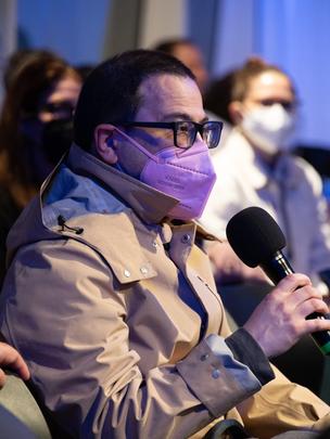 Masked audience member speaks during question and answer session