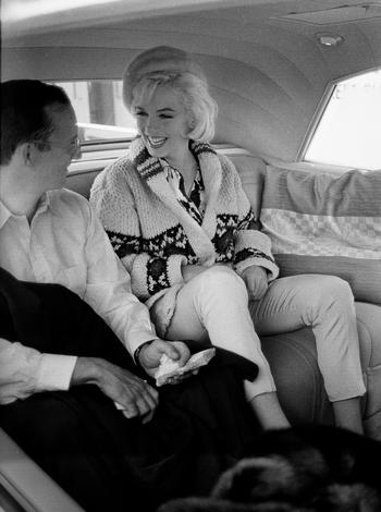 Marilyn Monroe with Wally Cox, her costar in “Something’s Got to Give,” driving to have dinner at Marlon Brando’s home,  wearing a sweater she purchased from Saks Fifth Avenue.
