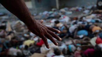 A man points to the hundreds of bodies piled up outside the morgue and main hospital in Port-au-Prince, Haiti.