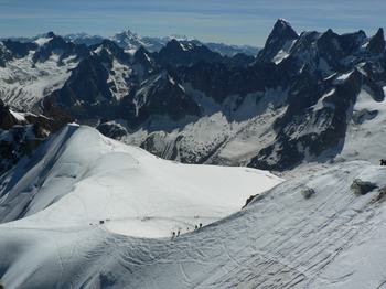 From the Aiguille du Midi, a mountain peak above Chamonix, ice climbers walk out on a vast snowfield.