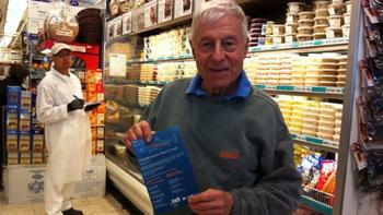 Saul Zabar, owner of Zabar's poses with a WQXR Trout Week pamphlet