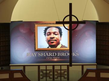A cross hangs from the cathedral ceiling while Rayshard Brooks is memorialized on a screen during his public viewing at Ebenezer Baptist Church on Monday, Jun 22, 2020, in Atlanta.