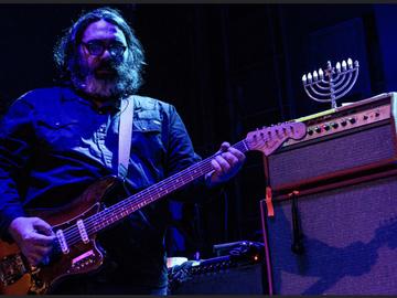 Yo La Tengo's guitar player plays guitar next to an amp with a menorah on top of it.