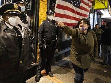 A woman yells as New York City Sheriffs stand guard outside of the restaurant Mac's Public House at the start of a rally against state and city mandates to stop indoor dining to control the spread of 