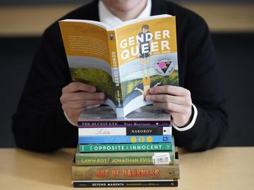 Amanda Darrow, director of youth, family and education programs at the Utah Pride Center, poses with books that have been the subject of complaints from parents in Salt Lake City. 