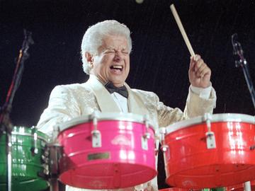 Percussionist Tito Puente plays a set of drums.