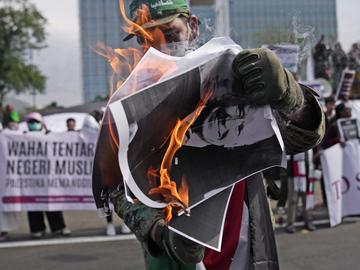 A protester burns a portrait of U.S. President Joe Biden during a rally supporting the Palestinian people outside the U.S. Embassy in Jakarta, Indonesia, Friday, Oct. 20, 2023. 
