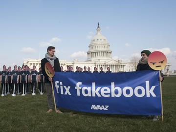 Men with sign saying 'Fix fakebook' stand next to  of 100 cardboard Mark Zuckerbergs in front of the U.S. Capitol