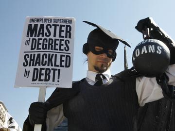 In this Oct. 6, 2011 photo, Gan Golan, of Los Angeles, dressed as the 'Master of Degrees,' holds a ball and chain representing his college loan debt, during Occupy DC activities in Washington. 