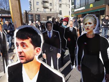 People look at the cardboard images of presidential candidates Volodymyr Zelensky, foreground, and Yulia Tymoshenko, right, in central Kiev, Ukraine, Thursday, March 28, 2019.