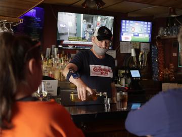 Bartender Greg Anderson, left, pours drinks for customers on the first day Tuner's Bar and Grill has reopened after being closed in an effort to slow the spread of the coronavirus Monday, May 4, 2020.