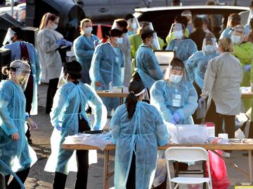 In this June 27, 2020, file photo, medical personnel prepare to test hundreds of people lined up in vehicles in Phoenix's western neighborhood of Maryvale for free COVID-19 tests.