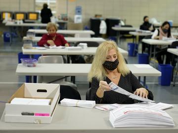 Linda Aftab works with other seasonal Board of Election employees to prepare mail-in ballots for counting in Linden, N.J., Thursday, Oct. 29, 2020. 