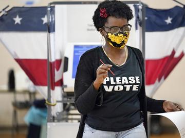Donta Stevenson carries her ballot to be processed as she votes at the Martha O'Bryan Center on Election Day Tuesday, Nov. 3, 2020, in Nashville, Tenn.