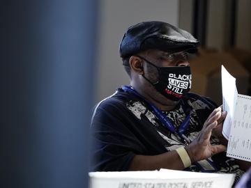 In this Nov. 4, 2020, file photo, an election worker holds a ballot as vote counting in the general election continues at State Farm Arena in Atlanta.