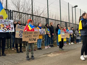 Protestors hold signs regarding Ukraine as they stand outside the security perimeter during a meeting of NATO defense ministers at NATO headquarters in Brussels, Wednesday, March 16, 2022. 