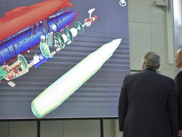 Russian President Vladimir Putin and President of National Research Center 'Kurchatov Institute' Mikhail Kovalchuk look up at an schematic image of a disassembled nuclear missile.