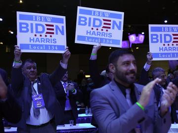 Members of the crowd hold up signs as President Joe Biden speaks at the 40th International Brotherhood of Electrical Workers (IBEW) International Convention at McCormick Place, Wednesday, May 11, 2022
