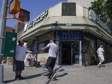 People walks in and out of a bodega in the Bronx section of New York, Friday, July 22, 2022. 