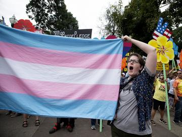 A supporter for the transgender community holds a trans flag in front of counter-protesters to protect attendees from their insults and obscenities at the city's Gay Pride Festival in Atlanta on Satur