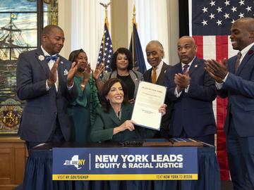This image provided by the Office of The Governor, shows New York Gov. Kathy Hochul, seated center, after she signed a bill, in New York, Tuesday, Dec. 19, 2023, to create a reparations commission.
