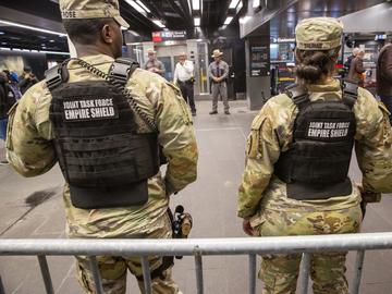 Members of the Armed Forces, including the National Guard, patrol the subway system in Penn Station as police officers check commuters' bags in New York on Thursday, March 7, 2024.