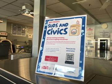 A sign promoting WNYC's Suds & Civics community engagement project -- featuring a cartoon graphic of a washing machine