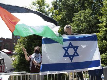 Counter protester Caren Ayden, of Pikesville, Md., carries an Israeli flag as students wave Palestinian flags during a demonstration against the Israel-Hamas war at George Washington University in Was