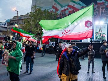  People wave flags as they demonstrate in support of the Iranian government on March 22, 2026 in central Tehran, Iran. 