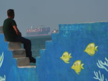 A Cargo boat navigates the sea behind a mural depicting fishes at the shoreline on April 28, 2026 on Qeshm Island, Iran in the Strait of Hormuz.
