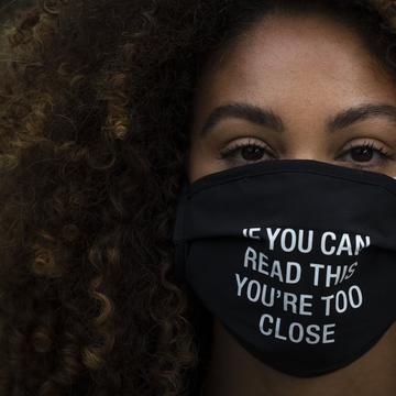 In this Monday, Dec. 7, 2020, file photo, Daisha Graf, 34, pauses for photos wearing a face mask with a message that reads 'If you can read this, you're too close,' in Los Angeles. 