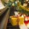 Yellow present lays on the keys of a piano with Christmas tree in the background