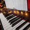 A piano with christmas lights and tree.