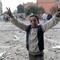 A young Egyptian anti-government demonstrator flashes victory signs as a stone battle rages between fellow demonstrators and pro-regime opponents at Cairo's Tahrir Square